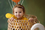 Kind im Korb mit Luftballons